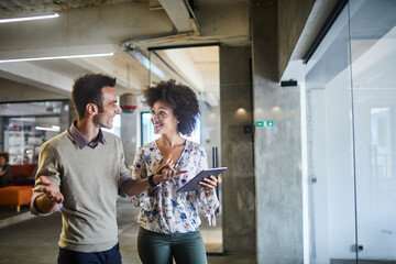 Two young people using a tablet together while working in a startup company office