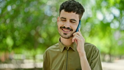 Sticker - Young hispanic man talking on smartphone smiling at park