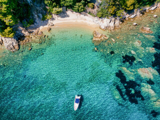 Wall Mural - a secluded beach with clear, emerald sea and an anchored boat at skiathos island, sporades, greece