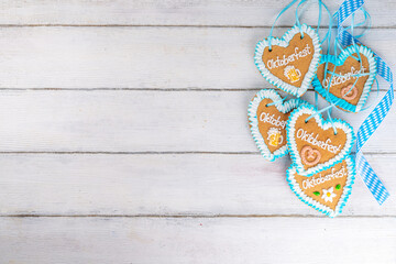 Wall Mural - Background for Oktoberfest invitation, menu, greeting card, White wooden table or wall empty surface with checkered ribbon and heart cookies with Oktoberfest symbols - flower, beer, pretzel top view