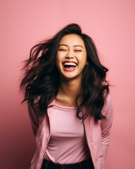 Wall Mural - portrait of happy young asian woman laughing isolated over pink background stock photo