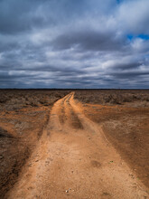 A Long Dirt Road Leading To A Desert Horizon With Dark Clouds Above In Northeastern New Mexico
