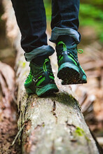 Closeup Of Green Hiking Shoes And Rolled Up Blue Jeans Walking Away On A Log In The Woods