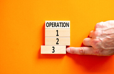 Time to operation 3 symbol. Concept word Operation 1 2 3 on wooden block. Businessman hand. Beautiful orange table orange background. Business planning and time to operation 3 concept. Copy space.