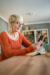 © Miljan Živković - one mature senior caucasian woman use mobile phone smartphone at home