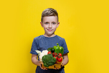 Wall Mural - Studio shot of smiling boy holding fresh pineapple, apple and orange on yellow background. The concept of healthy baby food