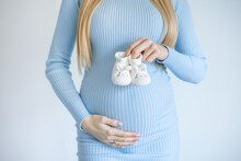 Small Shoes For The Unborn Baby In The Belly Of Pregnant Woman