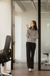 © Maria Vitkovska - Beautiful smiling Indian businesswoman holding mobile phone, looking away in modern office