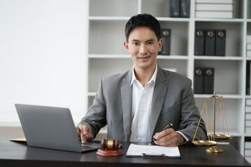 Wall Mural - Young smart Asian lawyer working in his office room with laptop computer. Law firm concept.