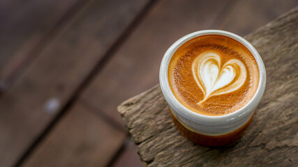 A cup of cappuccino coffee with soft foam on a wooden table. The coffee moment concept is everywhere.