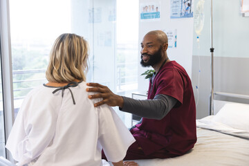 Wall Mural - African american male doctor talking to senior female caucasian patient at hospital