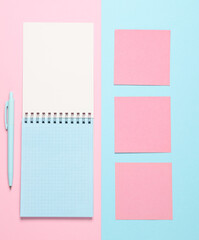 Wall Mural - Notebook with memo papers, pen on a blue-pink pastel background. Creative layout