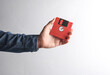 © splitov27 - Man's hand in denim shirt holding red floppy disk on gray background