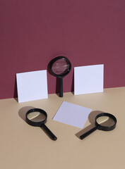 Wall Mural - Magnifying glasses with memo papers on burgundy beige background with shadow. Creative layout. Minimal business concept. Conceptual still life