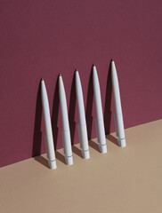 White Pens on burgundy beige background. Minimalism, conceptual business or education photo, creative layout