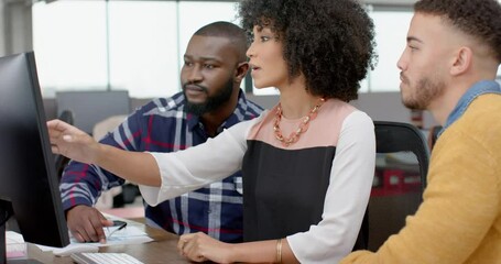 Wall Mural - three diverse male and female colleagues discussing over a computer at office