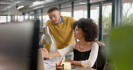 Wall Mural - diverse man and woman discussing over a computer at office