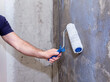 Construction work, plastering and wall priming. Builder's hand with paint roller. Copy space