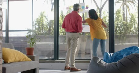 Wall Mural - rear view of diverse businesspeople discussing over memo notes on glass window at office