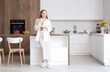 © Pixel-Shot - Happy young woman enjoying cup of coffee in modern kitchen