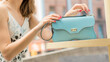 Beautiful girl with a stylish strap handbag on a terrace on the street in summer. Elegant women's blue leather shoulder bag