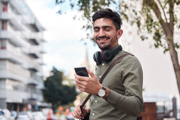 Fototapete - Travel, city and man with a phone outdoor for communication, connection or chat. Happy male student on urban street with smartphone and network for reading social media or navigation app notification