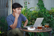 asian man using laptop in outdoor cafe