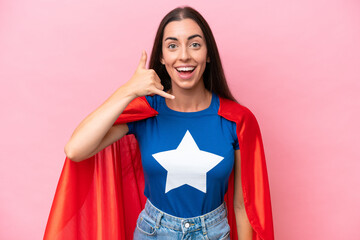 Wall Mural - Super Hero Caucasian woman isolated on pink background making phone gesture. Call me back sign