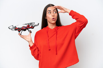 Wall Mural - Young caucasian woman holding a drone isolated on white background doing surprise gesture while looking to the side