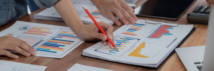 Leinwandbilder - Analyst team utilizing BI Fintech to analyze and pointing at financial dashboard paper office. Businesspeople examining report paper on table for business insight. Panorama shot. Scrutinize