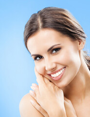 Wall Mural - Portrait of beautiful young happy smiling woman, over blue background