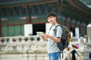 A young man who travels in a traditional Korean village and looks for directions while looking at a map