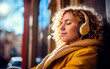 Blonde woman listening to music with headphones on the street.