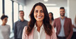 © Farnaces - Portrait of a smiling young businesswoman posing in the office with her work partners in the background. Generative AI