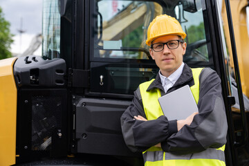 Aufkleber - Worker in a helmet with a digital tablet on the background of construction machine.