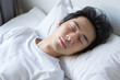 asian man wearing a white t-shirt sleeping peacefully in bed Generative AI