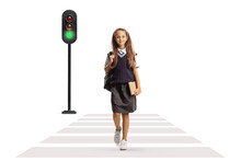 Full Length Portrait Of A Schoolgirl In A Uniform Carrying A Backpack And A Book And Crossing A Street