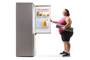 Sticker - Overweight woman in sportswear opening a fridge with food