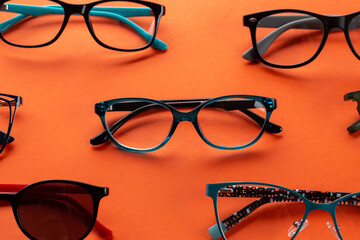 Set of glasses for vision on an orange background. Optical store, glasses selection, eye test, vision examination at optician