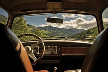 View From The Back Seat Of A Old Car. The View Through The Windshield Is Of A Mountainous Landscape With Green Trees And Blue Sky