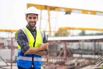 Wall Mural - Portrait building and construction worker, Hiapanic latin male wearing safety hard hat helmet standing with arms crossed at construction site and looking at camera