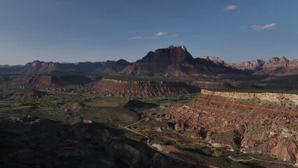 Wall Mural - Drone scene around rocky canyon mountains with grass under blue cloudy sky on the horizon