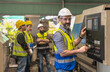 © Jack Tamrong - Caucasian Engineer factory man working with main control switch in industrial factory with teammates standing behind