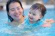 © TheVisualsYouNeed - happy and beautiful Asian woman holding her little baby girl playful - Korean mother and adorable daughter playing on water at resort swimming pool in Summer