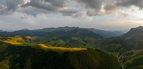 Sticker - Aerial view of an idyllic landscape with lush green hills with dramatic white clouds in the sky