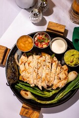 Sticker - Top view of a plate of roasted chicken and onions, with three small dishes of dipping sauce