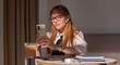 © Dana - young blonde girl in glasses and a white shirt sits in a cafe, holds a phone and talks on a video call