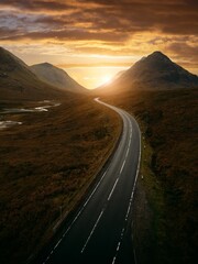 Sticker - a road winds through a mountain with a beautiful sunset in the background