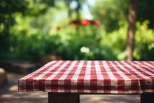 Red Checked Tablecloth On Wooden Background With Green Courtyard Blur. Summer Picnic Concept. AI