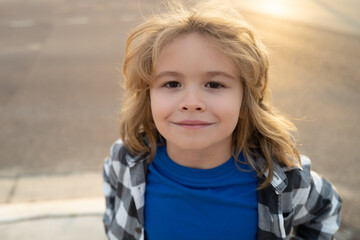 Lifestyle portrait of cute kid outdoors. Summer kids outdoor portrait. Close-up face child playing outdoors in summer park. Kid having fun outdoor on sunny summer day.